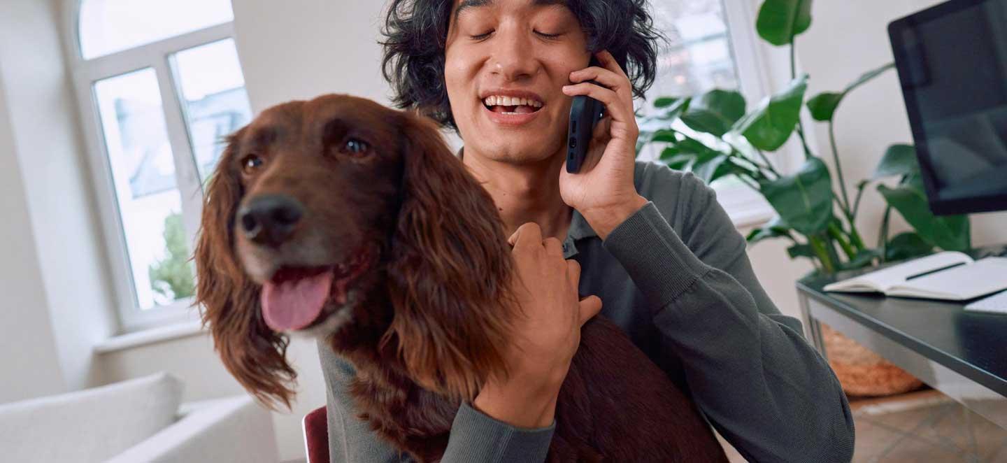 Herrchen telefoniert mit Hund auf Schoß
