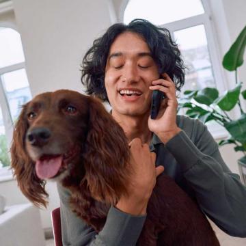 Herrchen telefoniert mit Hund auf Schoß
